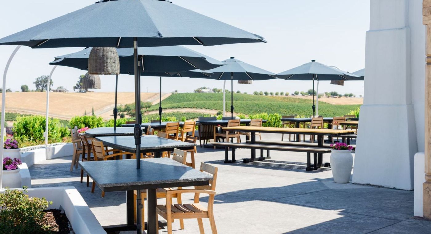 tables with umbrellas on outside patio with views of the vineyards